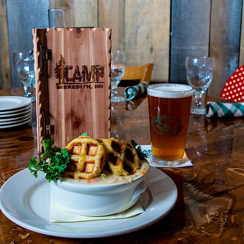 The image shows a table setting with a bowl of food, a glass of beer, a menu labeled 