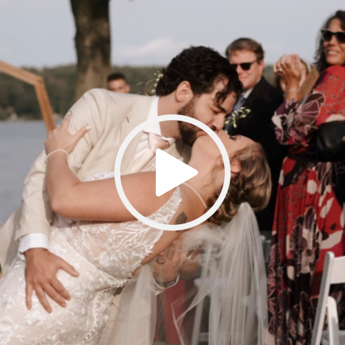 The image shows a wedding couple kissing, the groom in a beige suit and the bride in a white dress, while guests watch in the background.