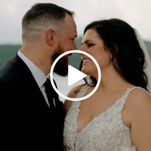 A bride and groom are close together, smiling joyfully at each other, with a play button superimposed in the center of the image.