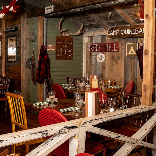 A rustic dining area with wooden furniture, antlers on the wall, checkered napkins, and signs reading 