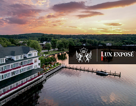 The image shows a large lakeside building at sunset, with 