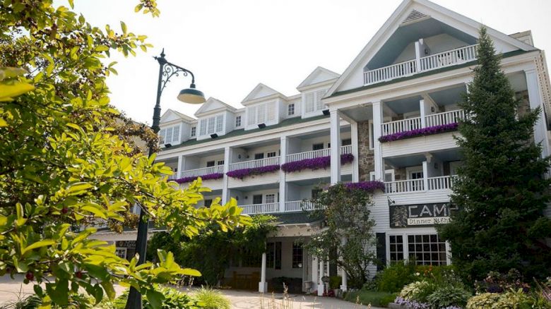 This image shows a charming multi-story building with balconies, surrounded by greenery and flowers, and featuring an ornate streetlamp.