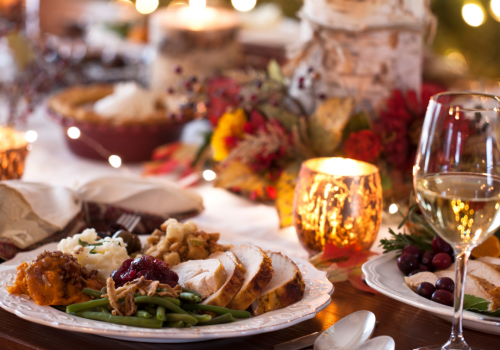 A festive dinner table with plates of food, candles, wine glasses, and holiday decorations, creating a warm and inviting atmosphere.