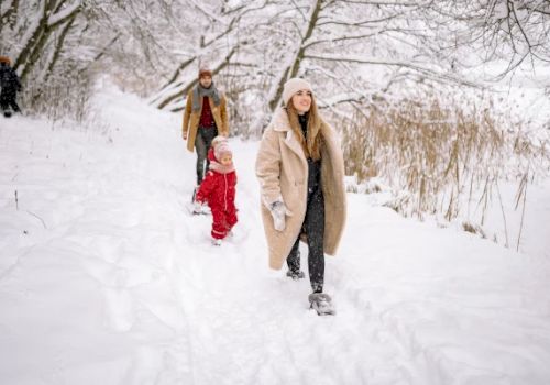 A family walks through a snowy path, bundled up in warm clothing.