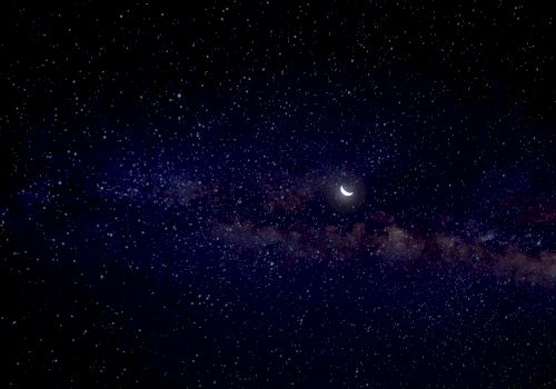 A starry night sky with a crescent moon and a hint of the Milky Way galaxy.